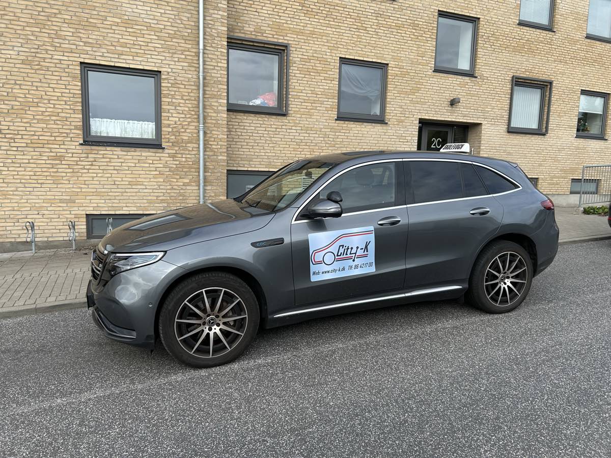 Grå Mercedes EQC elbil med City-K logo på siden — skolens vogn til bil- og trailerundervisning